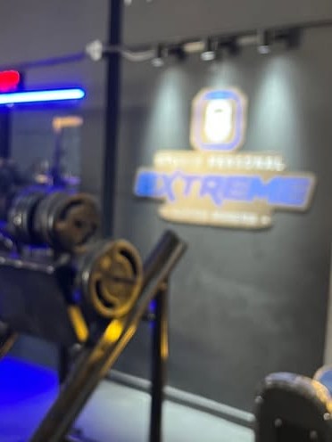 Área interna com equipamentos de musculação e iluminação neon
